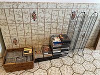 Overview of all items showing stacked CDs, DVDs, basket, and two metal storage stands against a tiled wall.