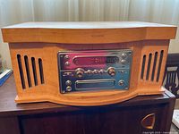 Front view of wooden record player console with speakers on side and control panel in center.