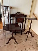 Four wooden stands grouped in a hallway: drawer stand, tall stand with weights, pedestal table and small round table.
