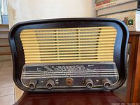 Front view of the vintage tube radio showing the large speaker grille and four front control knobs.