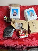 Group shot showing boxed duck figurines, Encore box with Santa figurine, stone bird and rock base