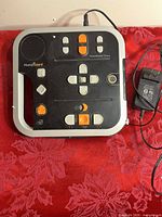 Top view of HumanWare VictorReader Stratus player with controls visible, power adapter alongside