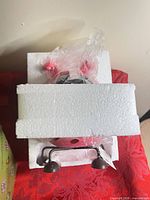 Interior Styrofoam packaging with partially visible pink figurine and metal legs