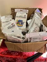 Open cardboard box filled with sealed Gift Toppers magnet packages