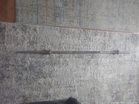 Full length image of 5-ft metal weightlifting bar showing both end stoppers and textured grip area.