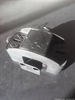 Close-up photo of the shiny metallic automatic card shuffler showing the spade symbol on top and card slots on sides.