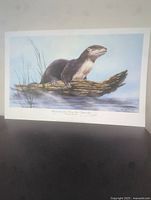Full view of the lithograph showing the otter on a log with water background, edges of the print visible indicating unframed condition.