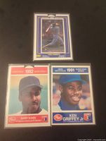 Photo showing three baseball cards: Jose Canseco 1991 in blue and white, Barry Bonds 1992 postcard, Ken Griffey Jr 1991 baseball card.
