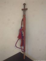 Full sword with sheath hanging vertically showing leather strap and tassels.