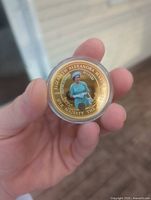 Obverse of coin showing Queen Elizabeth II sitting with green dress and hat, surrounded by inscriptions