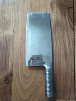 Top view of the stainless steel Asian meat cleaver on a wooden surface showing entire blade and handle