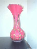 Side view of red Baijan blown glass vase with abstract yellow and black lines on bulbous lower base and long neck with ruffled top.