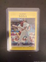 Front side of 1991 Fleer Sammy Sosa baseball card in protective holder showing Sosa in a batting stance in White Sox uniform with yellow border.