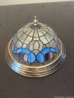 Image showing dome-shaped Tiffany style stained glass light fixture with frosted, blue and purple glass pieces and metal mounting base