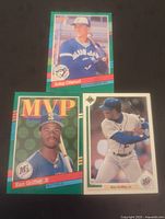 Three baseball cards laid out: Ken Griffey Jr. MVP card, Ken Griffey Jr. batting card, and John Olerud card in Blue Jays uniform.