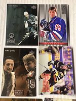 Close-up of four assorted hockey cards showing Mario Lemieux, Wayne Gretzky, Patrick Roy, and a Penguins player in action, highlighting card condition and print quality.
