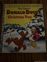 Front cover of Walt Disney's Donald Duck's Christmas Tree Little Golden Book showing Donald Duck and Pluto in snow