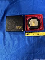 Vintage Coca-Cola themed electronic table lighter in original black Mellow Electronic box. Lighter features a round black plastic body, brushed metal front with gold-tone Coca-Cola bottle emblem.