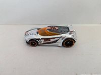 Chrome silver Hot Wheels die cast car with orange-tinted windshield and black-orange wheels, number 35 and checkered flag design, side view