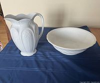 Photo of both serif white ironstone wash basin and pitcher with scalloped edges and floral embossing on pitcher