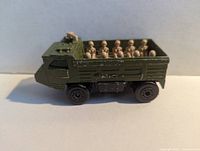 Side view of the green Matchbox Personnel Carrier toy with beige soldier figures in the truck bed showing condition and paint wear.