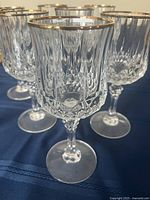 Close up of one crystal wine glass showing the faceted bowl and gold rim.