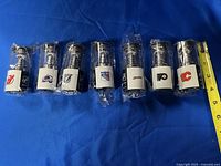 Seven Budweiser Mini Stanley Cup USB Memory Sticks lined up side by side on a blue surface showing each team's logo