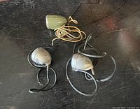 Three vintage microphones placed on a dark surface including one green housing and two metal Shure Brothers mics with cords