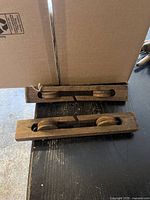 Two antique wooden clothesline separators placed horizontally showing pulleys and wood grain details.