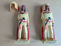 Front view of two vintage Indigenous Canadian souvenir figures, each with removable feathered headdress, showing details and colors.