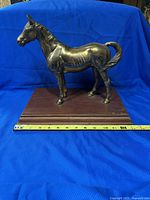 Front and side view of the vintage brass horse figurine on a rectangular wooden base with measuring tape showing approximately 13 inches length.