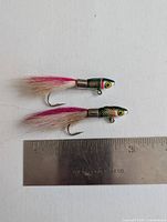 Two epoxy Rainbow Trout Streamers with detailed fish heads and feathered tails alongside a ruler for scale.
