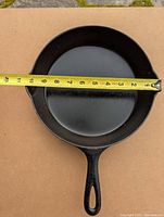 Top view of cast iron frying pan showing 8 inch diameter cooking surface with measuring tape.
