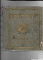 Front cover of the blue-green book with gold embossed lettering showing wear, creasing, and torn edges.