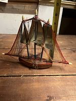 Front view of the vintage sailboat string art on a wooden surface with measuring tape showing height around 8 inches.