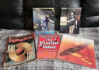 Photo showing five music-related books and magazines on a black couch: Kingston biography, Maclean's Gord Downie issue, Rolling Stone 'Playlist Issue', Rolling Stone '100 Albums of the 80s', and Led Zeppelin with abstract cover