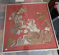 Full view of the framed Thailand stone rubbing artwork showing two traditional figures and surrounding design on a red background.