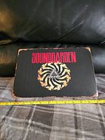 Front of metal Soundgarden sign showing band name and circular logo with distressed effect edges.
