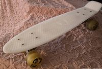 Close-up photo of the white plastic deck with a diamond grip pattern and visible bolt holes for the trucks.