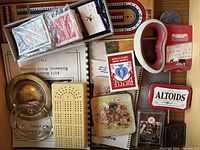 Box with playing cards, Altoids tin, small ashtrays, matchboxes, and paper materials