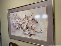 Framed watercolor painting showing floral composition in pastel colors with signature visible at lower right corner.