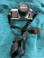 Front-facing view of camera with lens cap on and strap draped