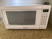 Front view of Panasonic inverter microwave oven displaying digital control panel and door with horizontal-striped glass window.