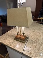 Photo of the working table lamp with beige fabric shade and wooden base on a granite countertop under indoor lighting.