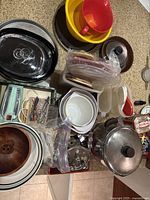 View of various kitchen items including pots, mixing bowls, plastic colanders, wooden salad bowl, and utensils on counter island