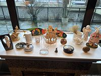 Tabletop decor items displayed on fireplace mantle including figurines, boxes, candle holders, and metal tray