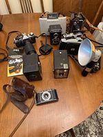 Overview of nine cameras and accessories on wooden table