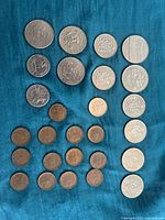 Photo showing the full layout of coins on a blue cloth, including Canadian pennies, nickels, quarters, and silver-colored coins.