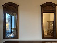 Two matching wall mirrors hung on wall, showing full front view with window and furniture reflected.