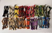 Full array of 100 skeins of embroidery thread laid out by color ranges including blacks, whites, yellows, reds, oranges, pinks, purples, greens and blues.